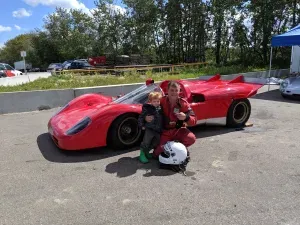 Chris with his family beside a red race car